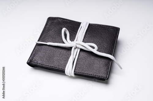 Obraz na plátne Black Leather Wallet Tied With Lace Over White Backdrop