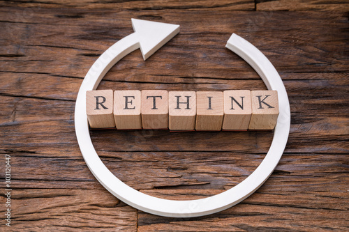 Wooden Blocks With Rethink Word And Arrow Over Wooden Surface photo