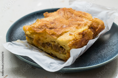 Turkish Borek with Minced Meat and Leek on Wooden Board with Paper.