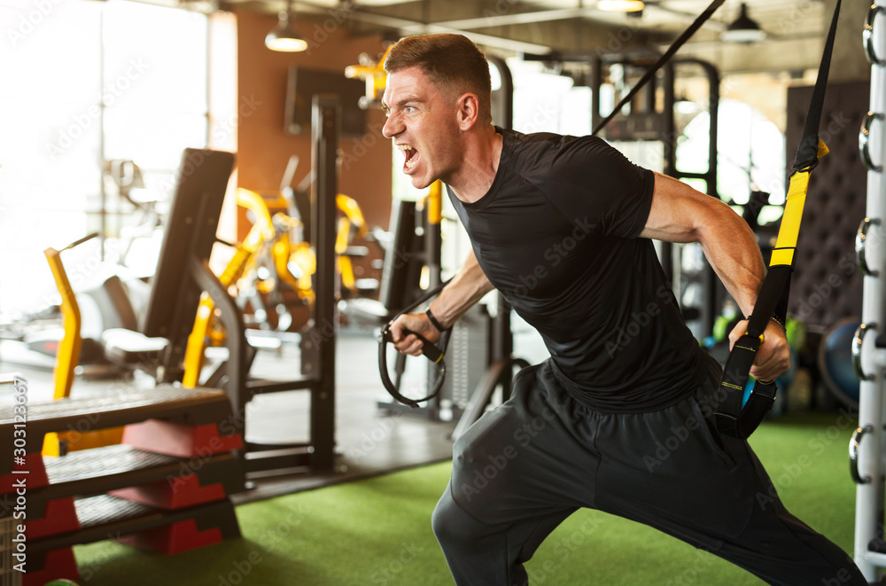 Young Caucasian man is doing workout in the gym Young Caucasian man is doing workout in the gym