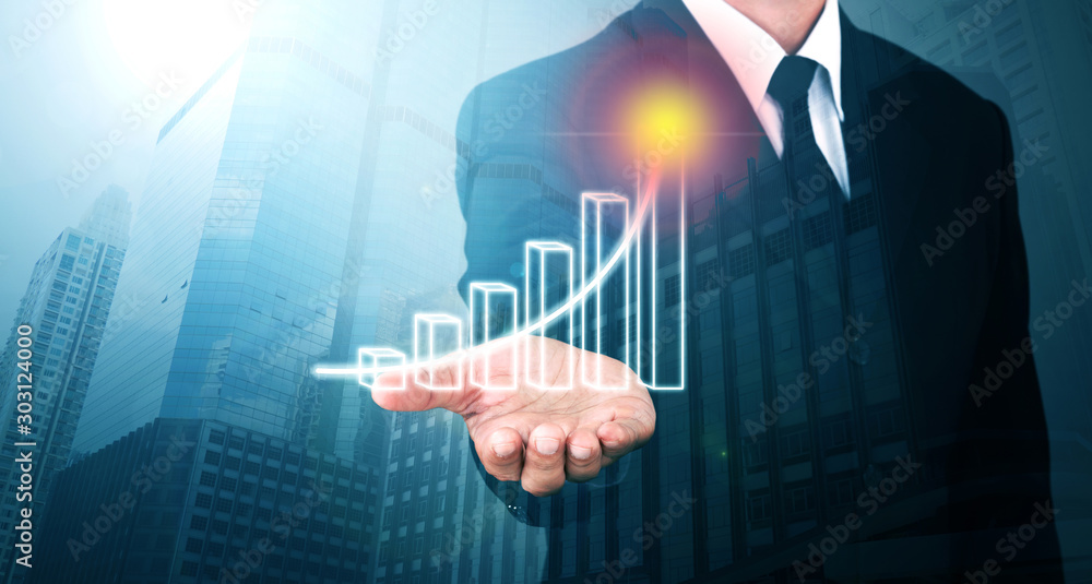 Man standing and shows outstretched hand with Bar Visual Graphic open palm on Light of Len flare and Bokh Blue Building background. COPY SPACE. Market Uptrend. Man standing and shows outstretched hand with Bar Visual Graphic open palm on Light of Len flare and Bokh Blue Building background. COPY SPACE. Market Uptrend.