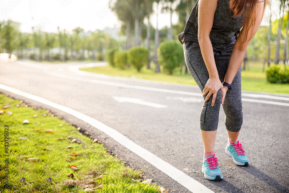 Female runner athlete knee injury and pain. Woman suffering from painful knee while running in the park. Female runner athlete knee injury and pain. Woman suffering from painful knee while running in the park.