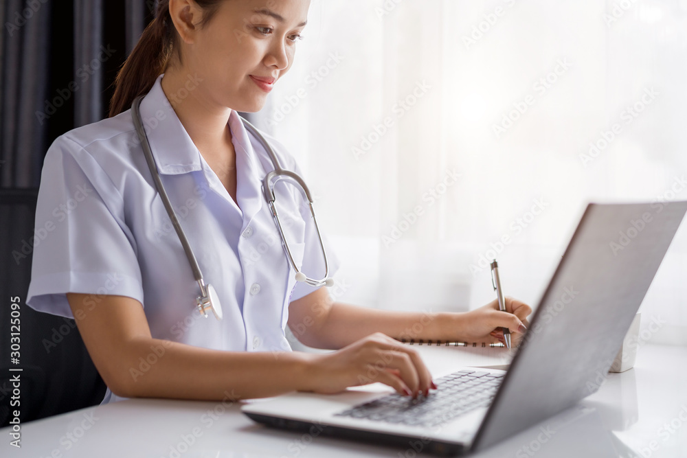 Young female doctor typing on laptop computer while working in the hospital Young female doctor typing on laptop computer while working in the hospital