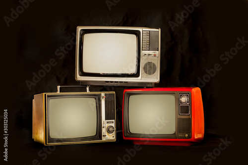 Three old retro television pile on a black background, old TV still life  photo