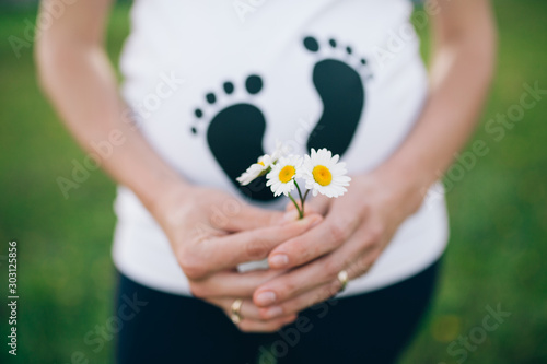 Maternity closeup of pregnant woman and flowers. 