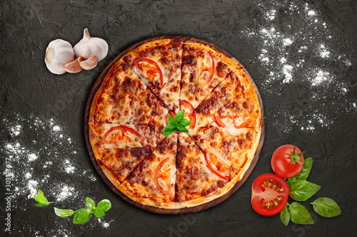 Pizza with vegetables, cheese and basil On a black background