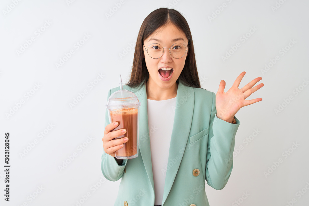 Young chinese woman drinking tomato smoothie over isolated white background very happy and excited, winner expression celebrating victory screaming with big smile and raised hands Young chinese woman drinking tomato smoothie over isolated white background very happy and excited, winner expression celebrating victory screaming with big smile and raised hands