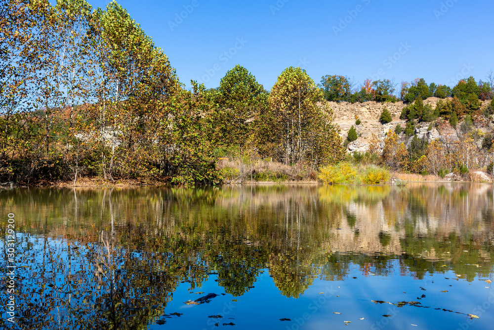 trees and rocky bluff reflected in a lake