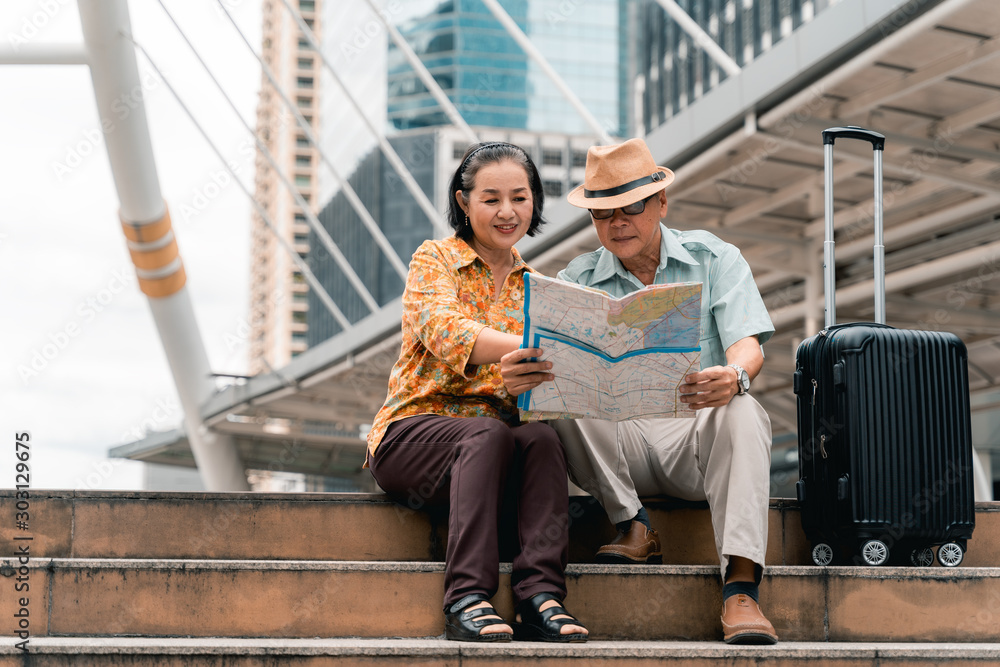 A couple of elderly Asian tourists visiting the capital happily and having fun and looking at the map to find places to visit.