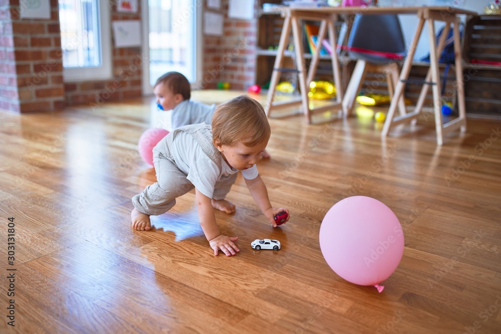 Fototapeta premium Beautiful toddlers playing around lots of toys at kindergarten
