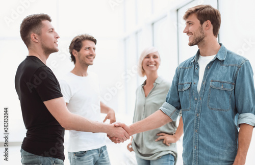 coworkers shaking hands in the office lobby.