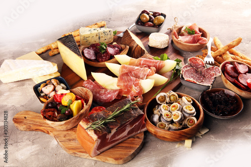 Italian antipasti wine snacks set. Cheese variety, Mediterranean olives, seafood salad, Prosciutto di Parma, tomatoes, anchovy and wine in glasses