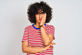 Young arab woman with curly hair wearing striped t-shirt over isolated white background thinking looking tired and bored with depression problems with crossed arms.
