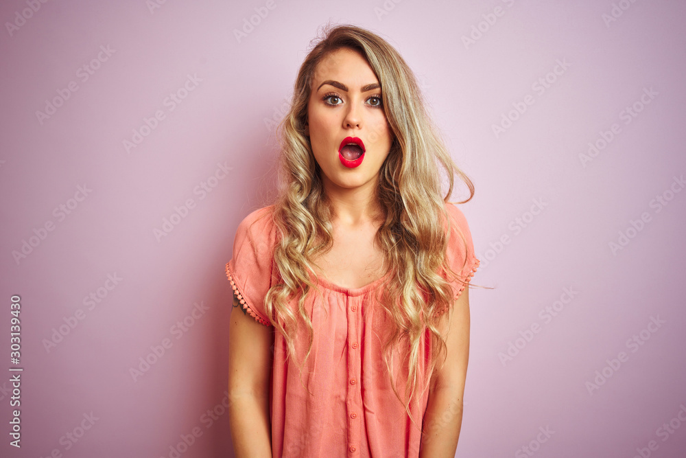 Young beautiful woman wearing t-shirt standing over pink isolated background In shock face, looking skeptical and sarcastic, surprised with open mouth Young beautiful woman wearing t-shirt standing over pink isolated background In shock face, looking skeptical and sarcastic, surprised with open mouth
