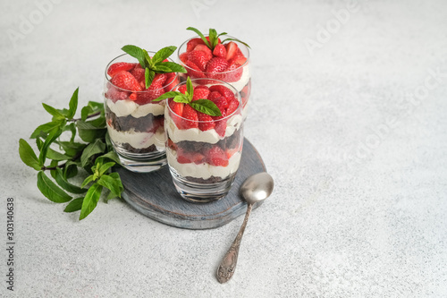 Beautiful dessert with fresh berries. Trifle with chocolate and strawberries on a light background copy space.
