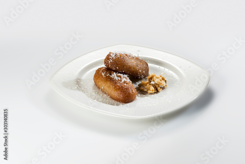 Riddled egg shaped sweet pastries in a white plate and on a white background.