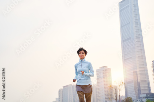 portrait of Asian woman jogging in city park at sunrise