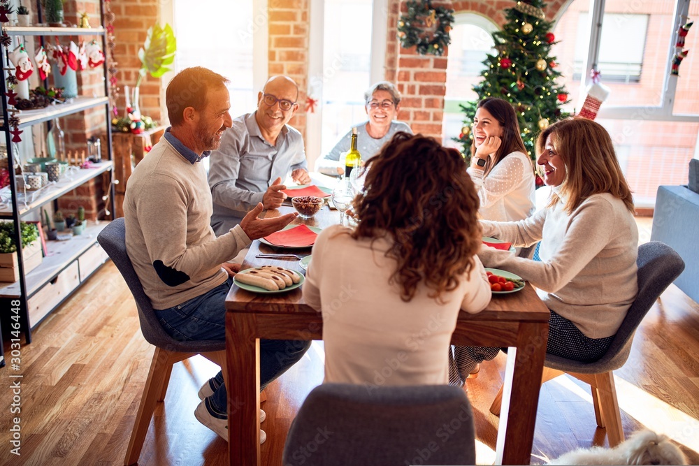 Family and friends dining at home celebrating christmas eve with traditional food and decoration, celebration of festive winter time