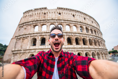 Photography Happy tourist taking a selfie in front of the Colosseum in Rome, Italy