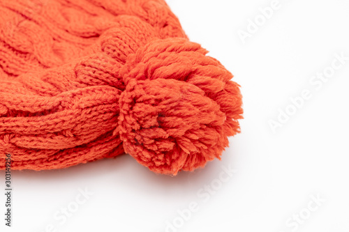 Orange knitted woolen hat beanie with pom pom on white background, winter concept