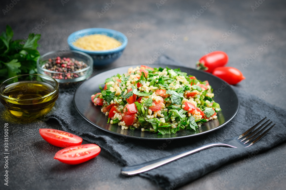 Traditional oriental salad Tabbouleh with bulgur and parsley on a dark background