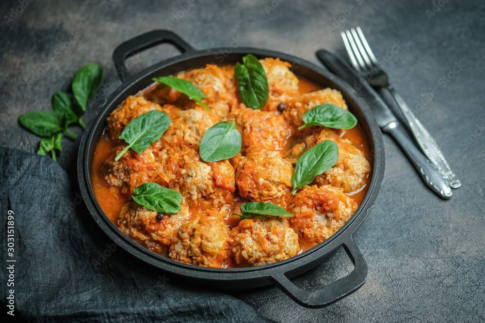 Meatballs in a pan with spinach leaves on a dark background copy space.