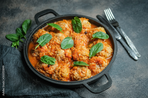 Meatballs in a pan with spinach leaves on a dark background copy space.