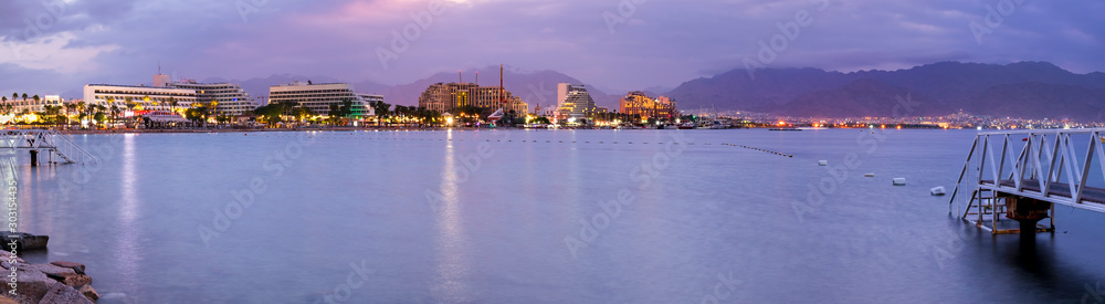 Obraz premium Night panoramic view on the central public beach of Eilat - famous tourist resort and recreational city in Israel