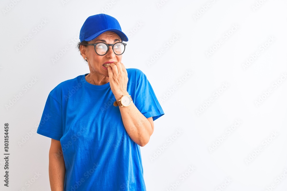 Senior deliverywoman wearing cap and glasses standing over isolated white background looking stressed and nervous with hands on mouth biting nails. Anxiety problem.