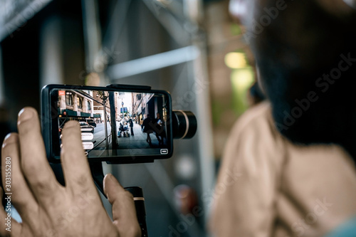 Man using phone with stabilizer and taking pictures and live video in New York city. Vlog, video blogging, street photography concept.
