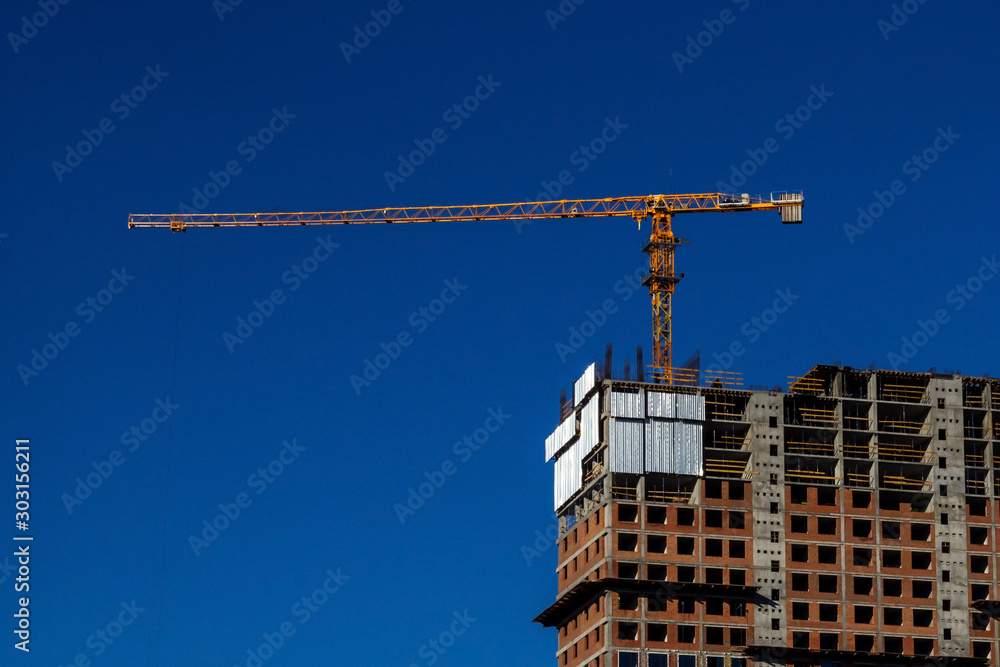 Construction of multi-storey house. Crane (machine) above the new building. Construction of multi-storey house. Crane (machine) above the new building.