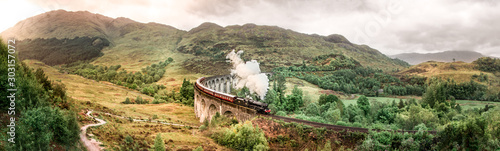 Glenfinnan Railway Viaduct with Jacobite steam train passing over. Harry Potter famous Glenfinnan viaduct, Scotland in cloudy weather with steam train. 