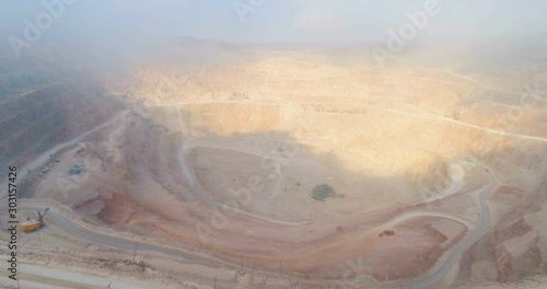 Aerial view industrial of opencast mining quarry with lots of machinery at work - view from above. Extraction of mineral, copper, gold.