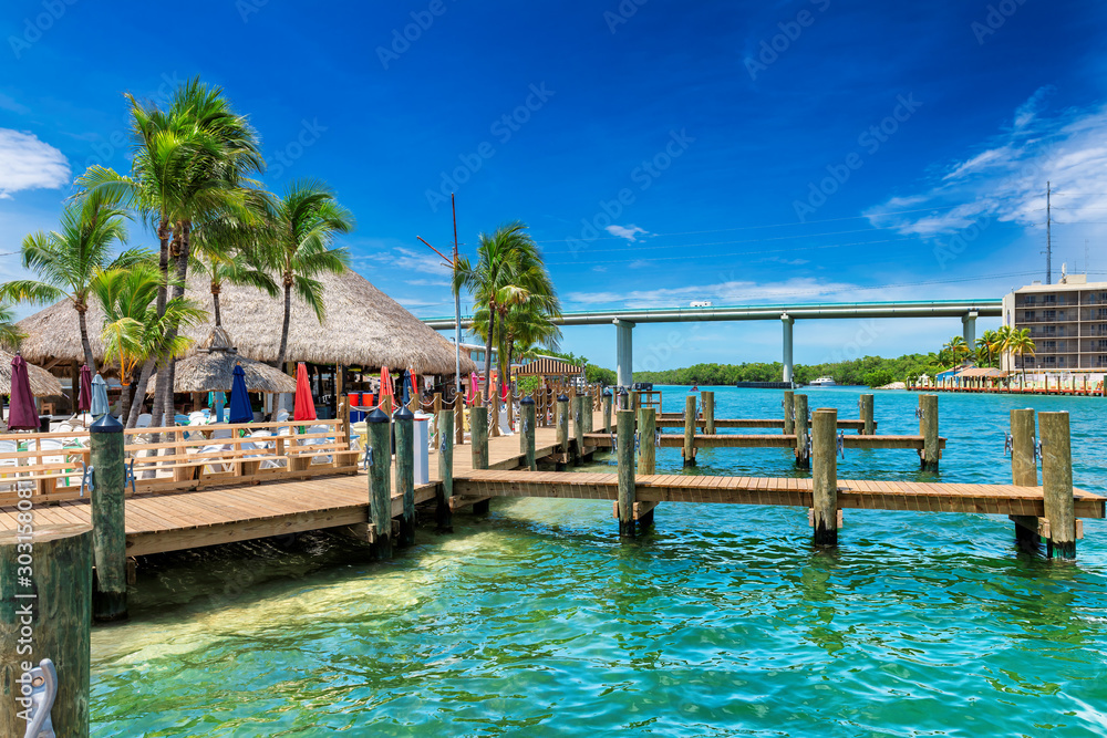 Florida keys resort and pier with palm trees on sunny beach.