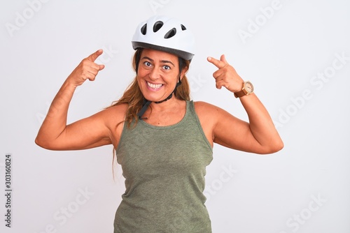 Middle age mature cyclist woman wearing safety helmet over isolated background smiling pointing to head with both hands finger, great idea or thought, good memory