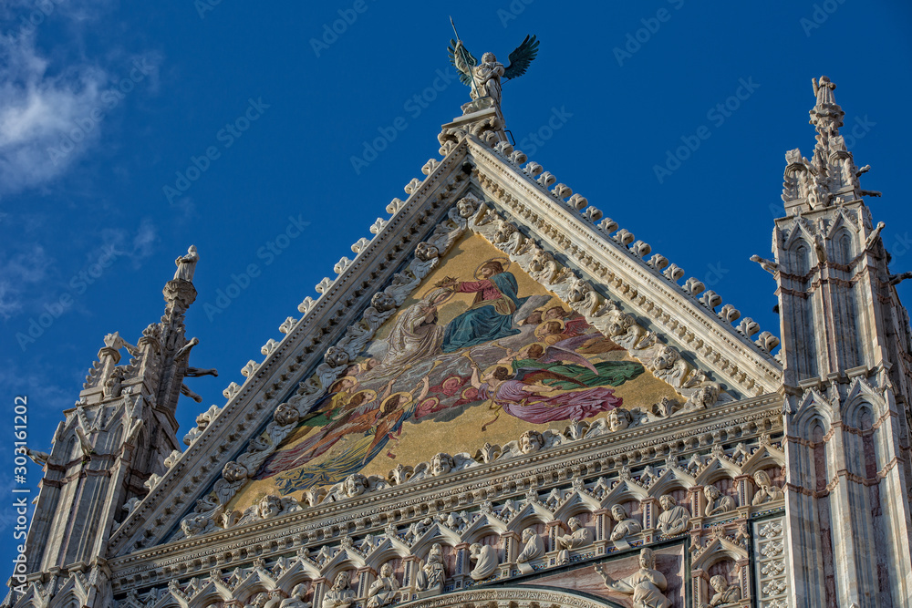 Siena Cathedral is a famous Italian romanesque-gothic cathedral with a striking facade is crowded with sculptures and architectural details, Tuscany, Italy