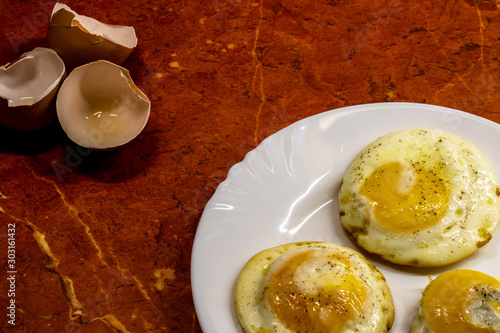 Three fried eggs on a plate and shells from them photo