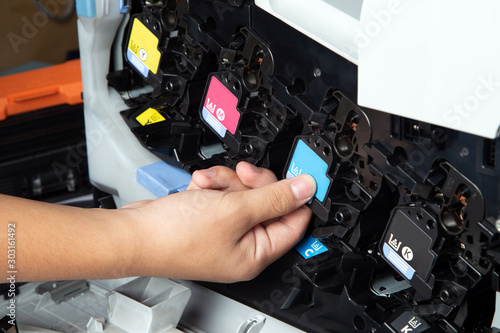 Business man or technician is pushing or pulling the printer equipment cartridges tone of laser jet multi function printer in the office. Close-up shot of CMYK ink cartridges for laser printer. photo