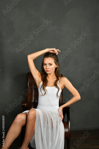 girl in a white translucent dress in red pointes on a gray background