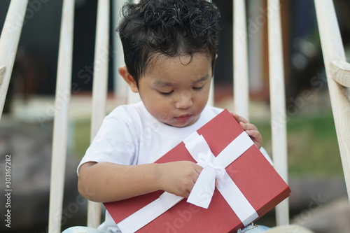 Happy cute Asian boy 2 year old wear white shirts, embracing red gift boxes, new year festivals, Christmas birthdays, or important festivals.         