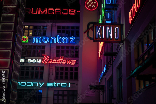 Glow, bright, words in neon light reflected everywhere in narrow dark street, during the night in Wroclaw, Poland