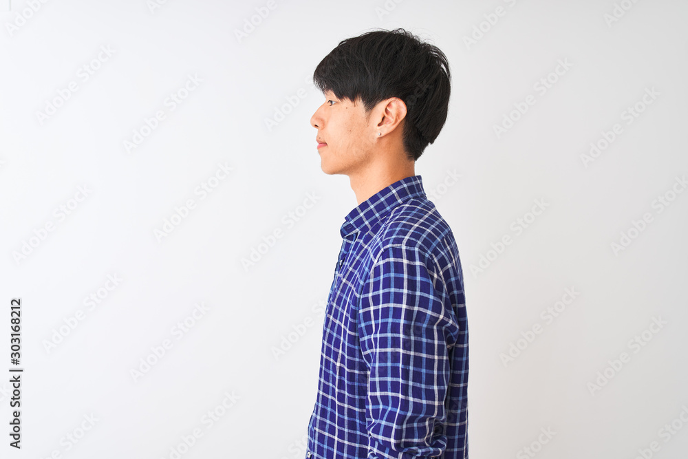 Young chinese man wearing casual blue shirt standing over isolated white background looking to side, relax profile pose with natural face with confident smile. Young chinese man wearing casual blue shirt standing over isolated white background looking to side, relax profile pose with natural face with confident smile.