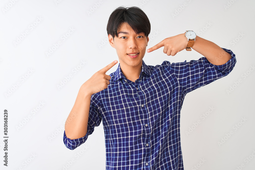 Fototapeta premium Young chinese man wearing casual blue shirt standing over isolated white background smiling cheerful showing and pointing with fingers teeth and mouth. Dental health concept.