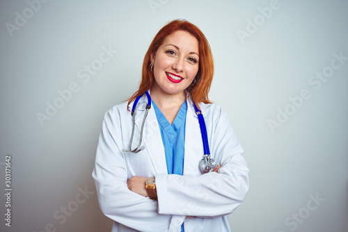 Young redhead doctor woman using stethoscope over white isolated background happy face smiling with crossed arms looking at the camera. Positive person.