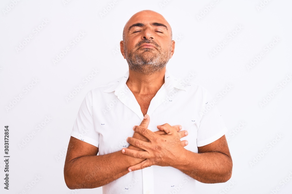 Middle age handsome man wearing elegant shirt standing over isolated white background smiling with hands on chest with closed eyes and grateful gesture on face. Health concept. Middle age handsome man wearing elegant shirt standing over isolated white background smiling with hands on chest with closed eyes and grateful gesture on face. Health concept.