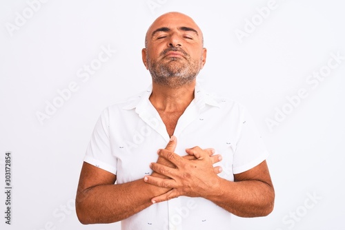 Middle age handsome man wearing elegant shirt standing over isolated white background smiling with hands on chest with closed eyes and grateful gesture on face. Health concept.