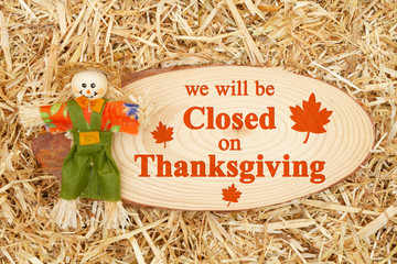 Closed for Thanksgiving message with a scarecrow with wood sign