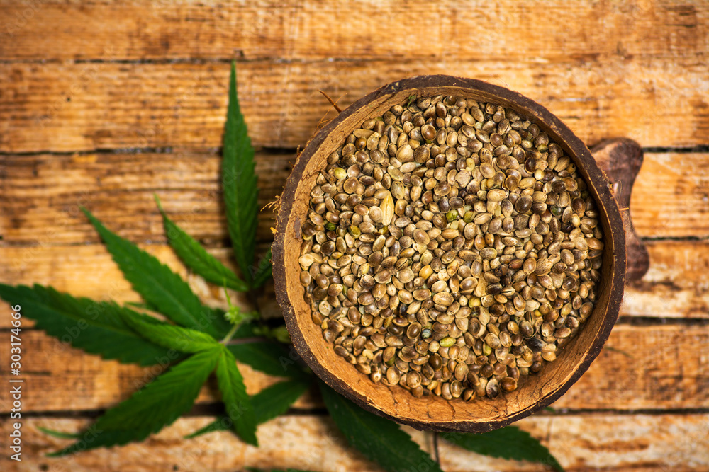 Cannabis seeds and marijuana leaves in a bowl on Cannabis seeds and marijuana leaves in a bowl on