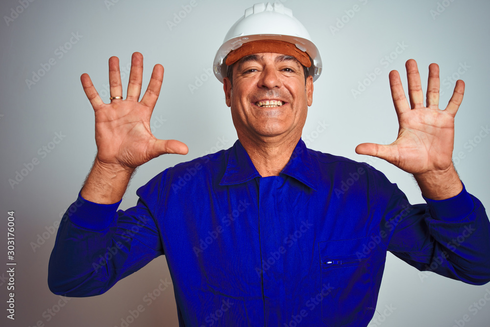 Handsome middle age worker man wearing uniform and helmet over isolated white background showing and pointing up with fingers number ten while smiling confident and happy.