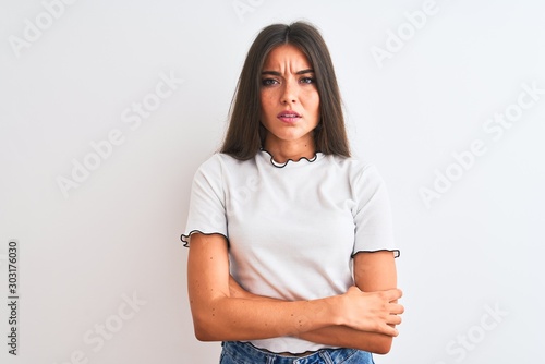 Young beautiful woman wearing casual t-shirt standing over isolated white background skeptic and nervous, disapproving expression on face with crossed arms. Negative person.